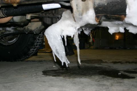 2003 Jeep TJ - Ice formations hang from the undercarriage of a 2003 Jeep TJ, with a tire equipped with snow chains visible.
