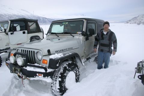 2003 Jeep TJ - A group of Jeeps are stuck in deep snow, with a man standing beside one of them.