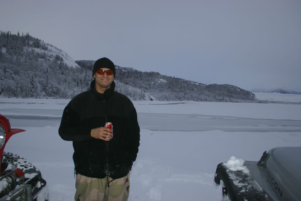 2003 Jeep TJ Rubicon in snow, front right corner visible, with a man standing in front of a frozen lake