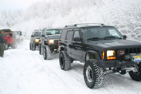 2003 Jeep TJ - Several Jeep Cherokees drive in a line through a snowy landscape.