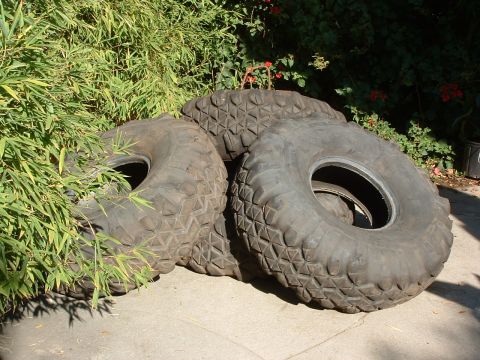 2004 Toyota Tacoma - Several large, aggressive tread off-road tires are piled up outdoors.