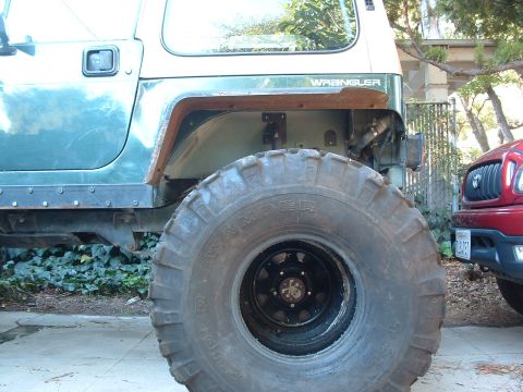 2004 Toyota Tacoma - A modified Jeep Wrangler is shown next to a red Toyota Tacoma, with the Wrangler's large tire dominating the foreground.