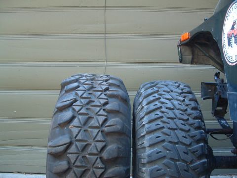 2004 Toyota Tacoma - Two off-road tires are shown next to the fender of a dark green vehicle.
