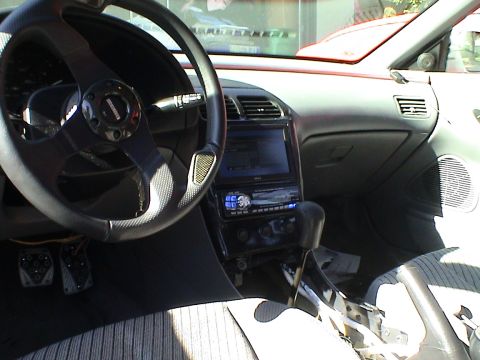 1997 Ford Probe - The interior of a car shows a custom steering wheel, a double-DIN head unit, and a modified gear shifter.