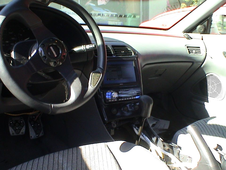 car interior with aftermarket steering wheel, stereo, and shifter