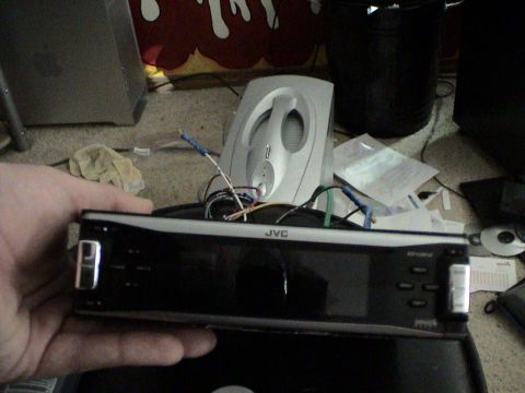 1997 Ford Probe - A JVC car stereo is being held, with wires connected, ready for installation or removal.