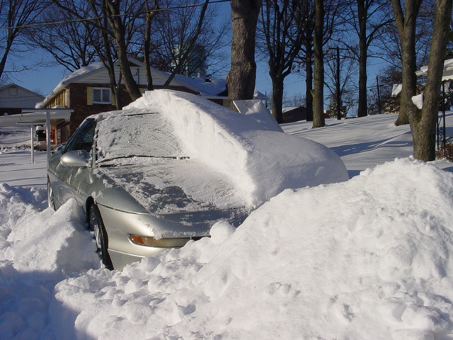 Silver 1994 Ford Probe buried in snow, front view