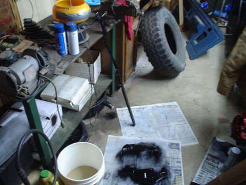 1984 Ford Bronco - Workbench setup for painting vehicle parts, with a spare tire and door visible.