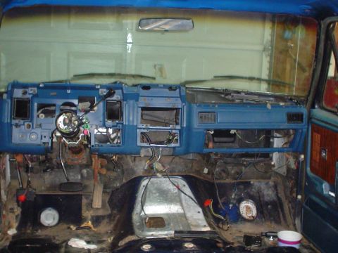 1984 Ford Bronco - The interior of a vehicle is shown in a state of disassembly, with the dashboard removed and wiring exposed.
