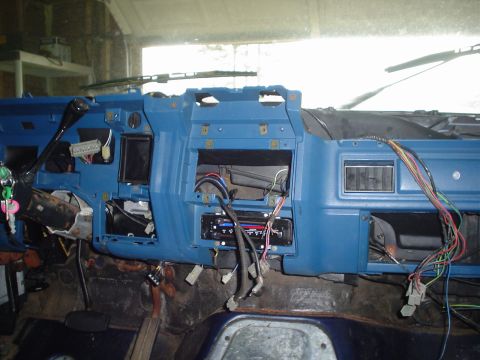 1984 Ford Bronco - The dashboard of a vehicle is disassembled, showing exposed wires and an empty radio slot.