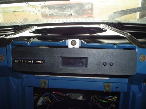 1984 Ford Bronco - Close-up of a vehicle's dashboard showing a digital clock unit with date and time functions.