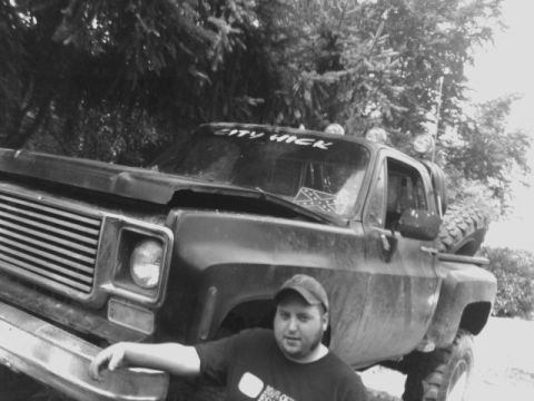 1976 Chevrolet C/K Pickup - A man poses in front of a lifted pickup truck with a rebel flag sticker on the windshield.