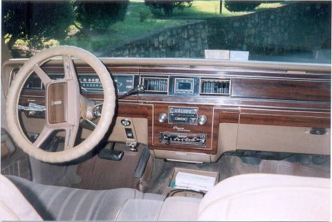 1982 Ford Crown Victoria LTD - The dashboard of a car shows wood grain accents and a beige steering wheel.
