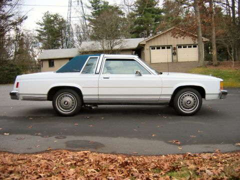 1985 Ford Crown Victoria LTD - Side view of a white 1985 Ford Crown Victoria LTD coupe with a blue vinyl roof.