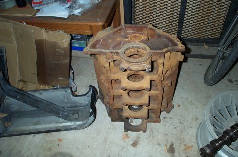 1978 Dodge Power Ram - A heavily rusted engine block sits on a concrete floor next to a bumper and other parts.