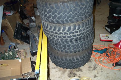 1978 Dodge Power Ram - A pile of tires sits in a cluttered garage next to various automotive parts and supplies.