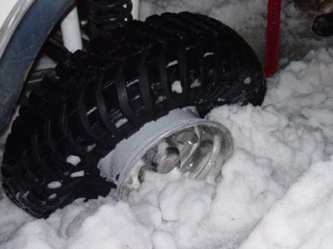 1986 Ford Bronco - A vehicle's tire is deeply embedded in snow, suggesting it may be stuck.