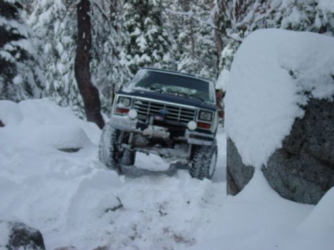 1986 Ford Bronco - This 1986 Ford Bronco is navigating a challenging snowy path in a forest.