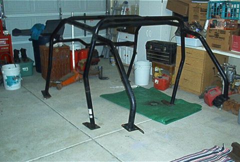 1986 Ford Bronco - A black metal roll cage is shown disassembled in a garage setting.