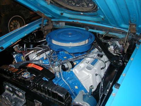 1987 Ford Bronco - Close-up of a blue engine bay a chrome air cleaner and "CAUTION" sticker on the radiator hose cover.