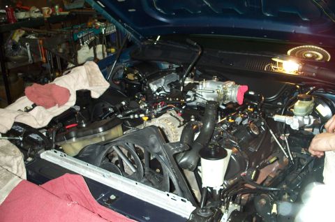 1998 Ford Crown Victoria - The engine bay of a 1998 Ford Crown Victoria is visible with the hood up, revealing various mechanical parts.