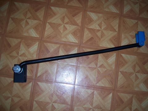 1983 Ford Bronco - A black metal bar with a blue end piece and a bolt is shown against a wood-patterned tiled floor. The part appears to be a component for a…