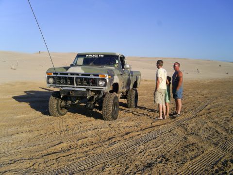 1977 Ford F-150 - Modified 1977 Ford F-150 pickup truck in a desert landscape with people observing.