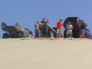 1977 Ford F-150 - Group of people and vehicles on sand dunes with a clear blue sky above.
