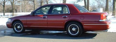 1999 Ford Crown Victoria - Side view of a red sedan with black wheels parked outdoors in winter.