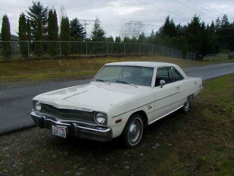1993 Ford Bronco - A white 1974 Dodge Dart coupe is parked on the side of a road, with trees and a power line tower in the background.