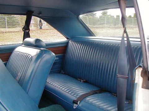 1993 Ford Bronco - The interior of a vintage vehicle features blue vinyl seats and seatbelts, with a view of the outdoors through the rear window.
