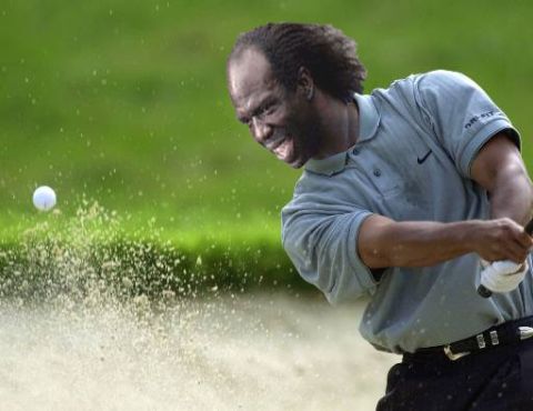 1991 Ford Bronco - A golfer emerges from a sand trap with a powerful swing, kicking up a cloud of sand.