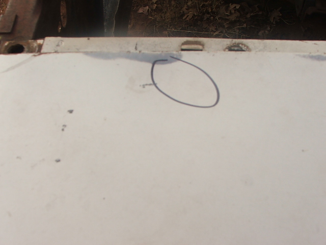 Close-up of a white car hood with a circled area and some dark spots