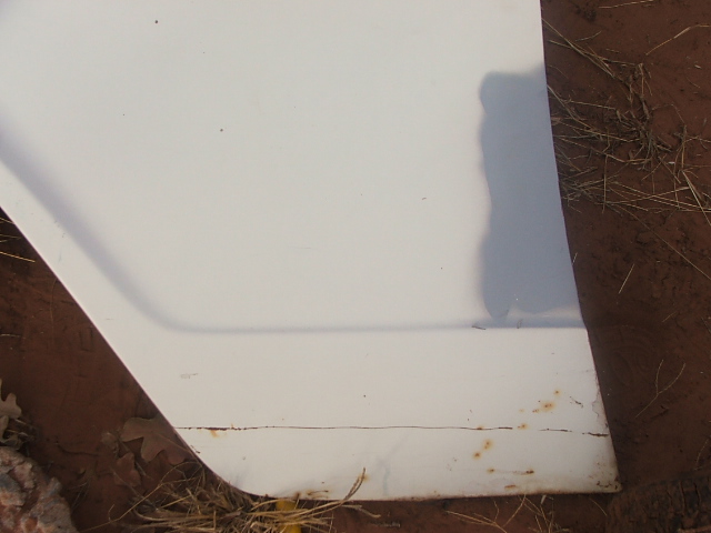 White car door edge showing rust and dirt on the lower trim