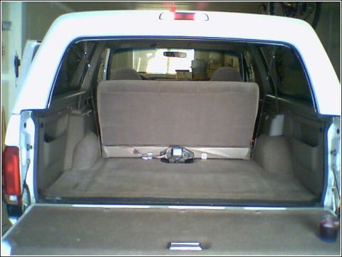 1995 Ford Bronco - The cargo area of a white Ford Bronco is viewed from the rear, with the tailgate open.