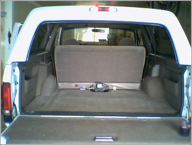 White Ford Bronco interior cargo area, rear seats folded down, showing carpeted floor and side panels