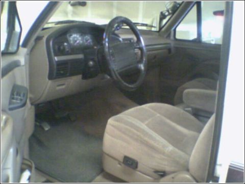 1995 Ford Bronco - The interior of a 1995 Ford Bronco, its dashboard, steering wheel, and cloth seats.