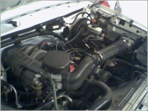1995 Ford Bronco - The engine compartment of a vehicle is shown, with various mechanical parts and wiring.