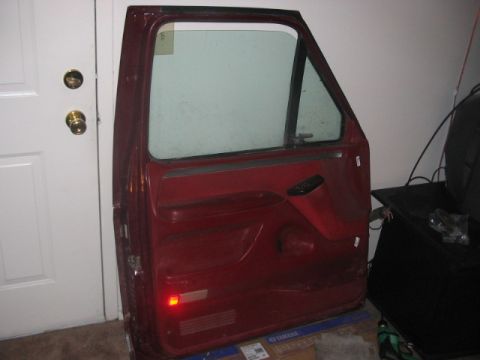 1991 Ford Bronco - A single red car door is shown, likely for a truck or SUV, indoors.