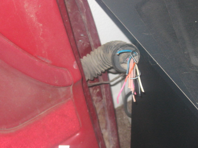 close-up of a red interior panel with a gray corrugated conduit holding exposed wires