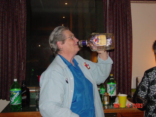 person drinking from a large bottle of Crown Royal, Sprite and other drinks on table