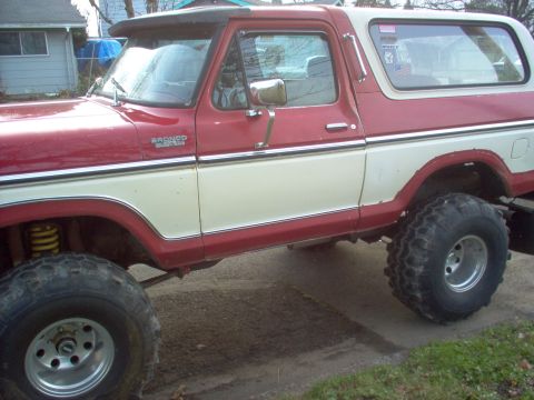1992 Ford Bronco - This two-tone red and white Ford Bronco features a prominent side badge indicating it is a Bronco.