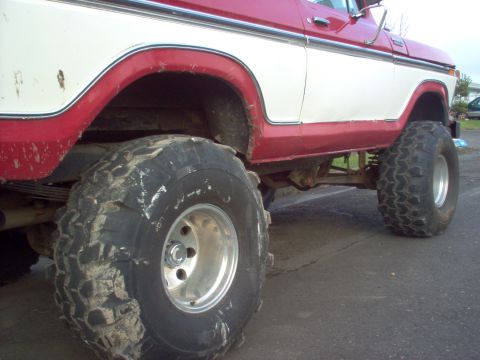 1992 Ford Bronco - This lifted Ford Bronco features a two-tone red and white paint scheme and aggressive off-road tires.