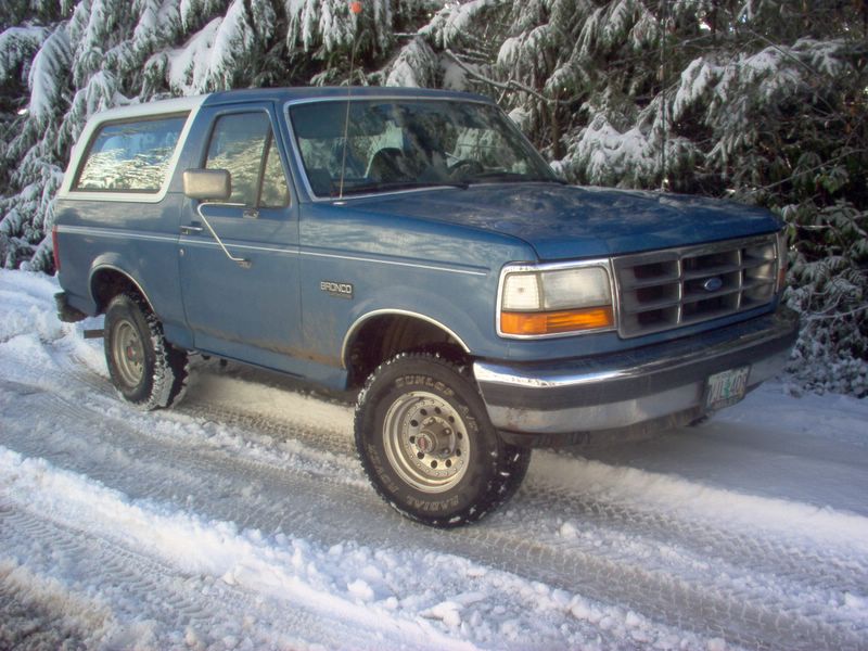1992 Ford Bronco parked on a snowy road with trees in the background