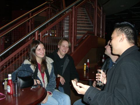 1996 Ford Probe - A group of friends enjoy conversation and drinks in a dimly lit establishment with a prominent staircase.
