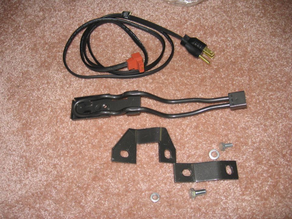 Engine block heater kit with cord, element and mounting brackets on carpet