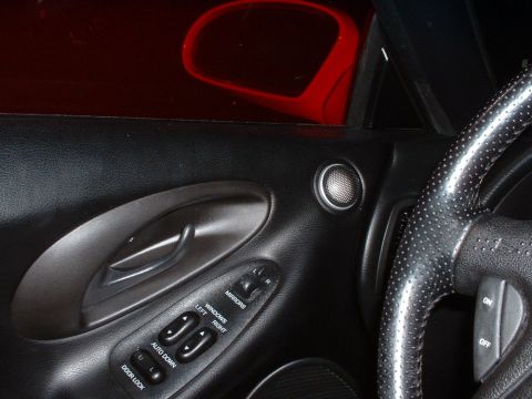 1995 Ford Probe - Close-up of a car's interior door panel, showing window controls, a speaker, and part of the steering wheel.