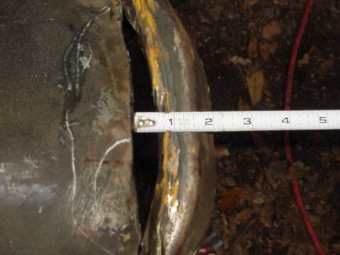 1989 Ford Bronco - A tape measure is used to gauge the size of a gap on a weathered metal component.