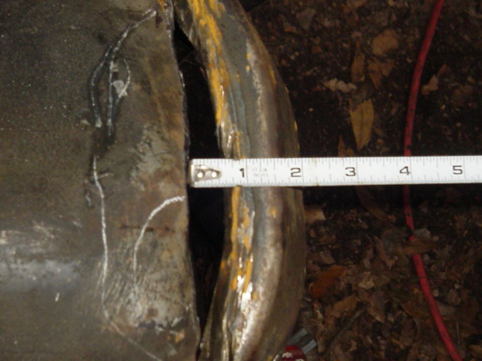 measuring a gap on a rusty metal part with a tape measure