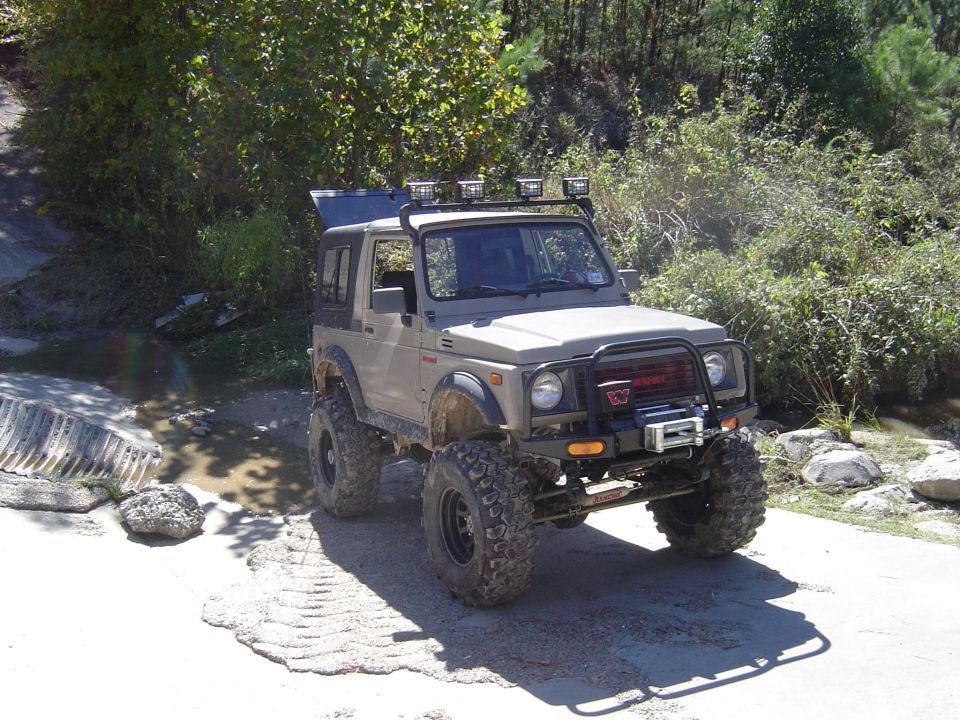 Tan Suzuki Samurai with off-road tires, winch, and roof rack